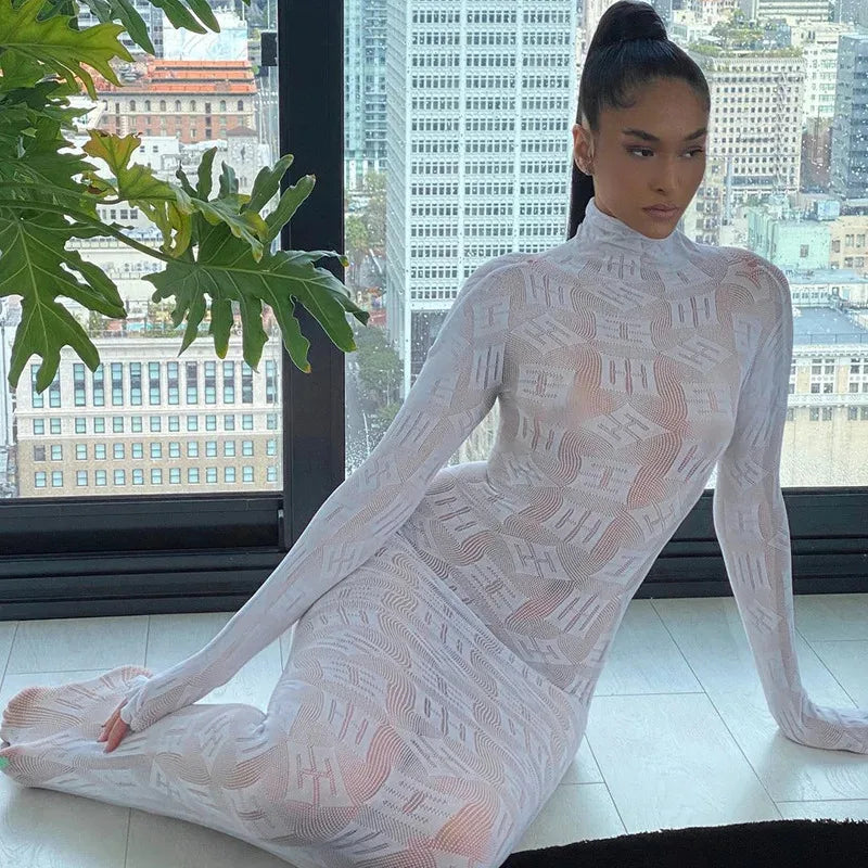 Model wearing a white sheer long sleeve club dress with a high neck sitting on floor by window