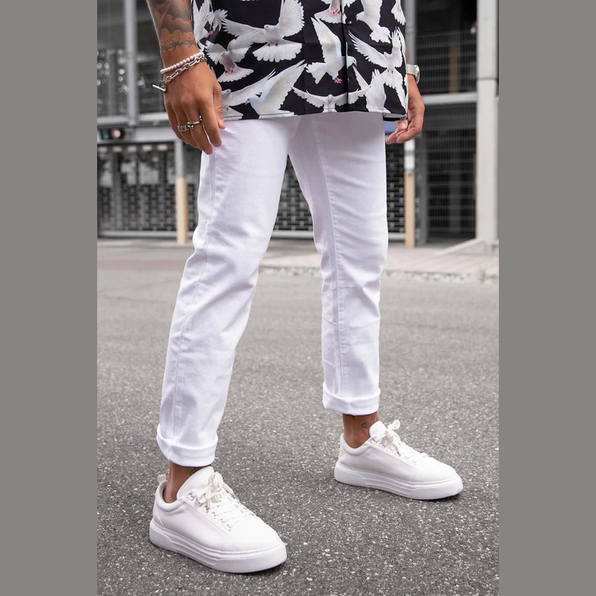 White slim fit jeans for men paired with white sneakers on an urban street