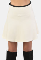 White skirt with black trim worn by a person on a white background