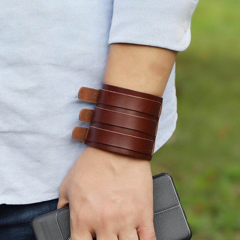 Wide cuff pu leather bracelet in rich brown color worn on a man's wrist with a smartphone