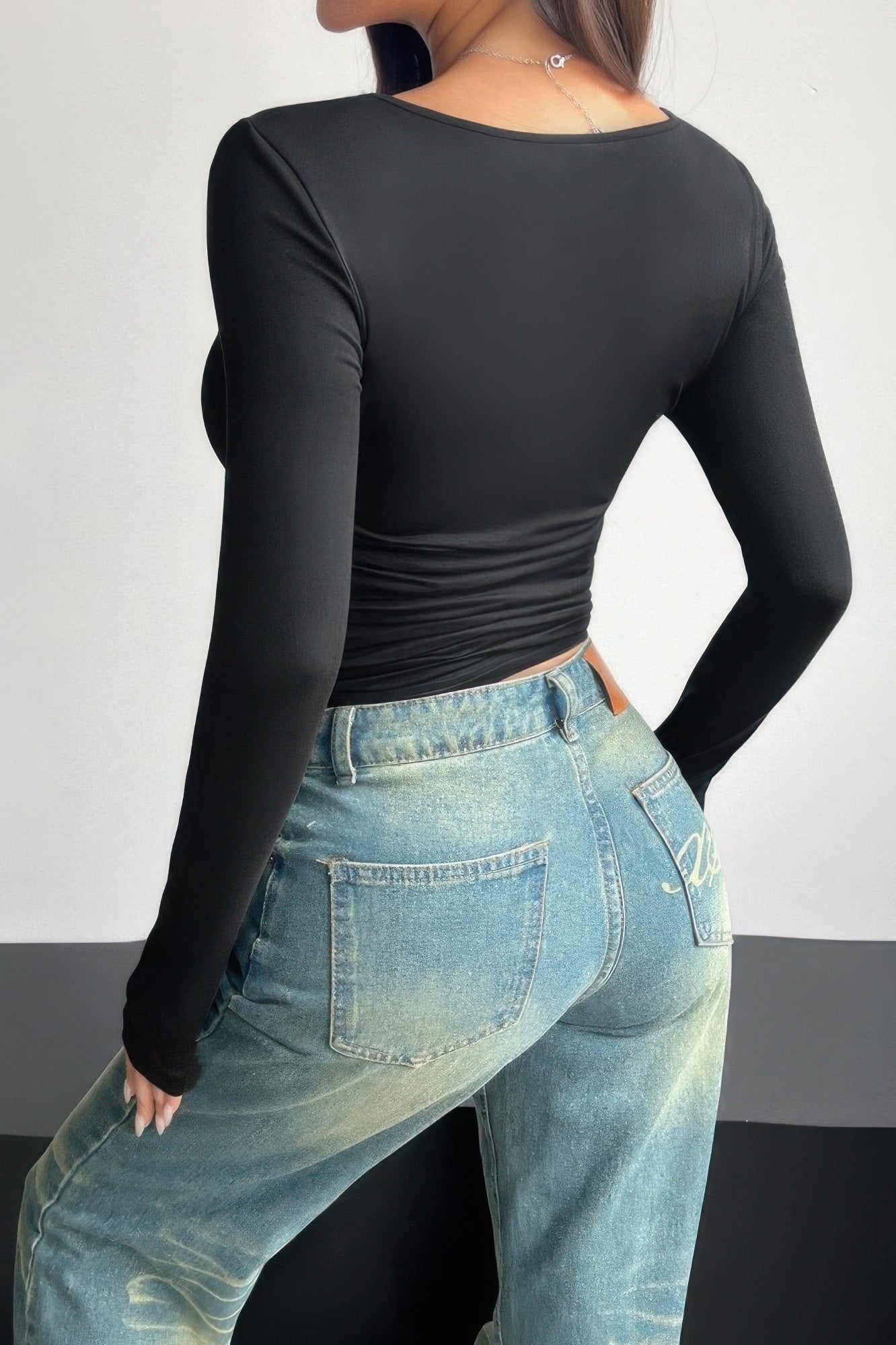 Plain black ruched tee for women with long sleeves paired with high-waisted denim jeans