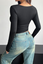 Plain black ruched tee for women with long sleeves paired with high-waisted denim jeans