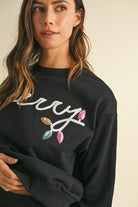 Woman wearing black womens cozy Christmas matching set sweater with holiday light design