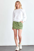 BLUME AND CO. women's drawstring skirt with pockets in green worn with white sweatshirt and sneakers