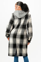 Back view of a women's hooded plaid coat in black and white with a gray hood and side slits