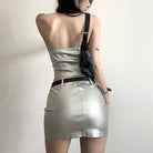 Back view of a womens metallic skirt and crop top set in silver with a black shoulder bag