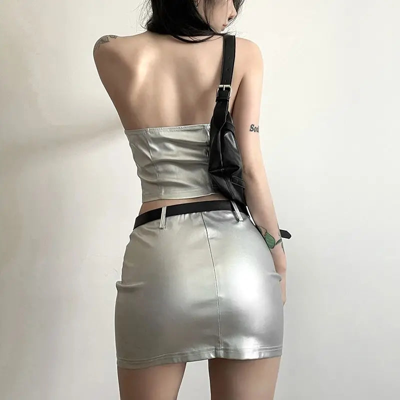 Back view of a womens metallic skirt and crop top set in silver with a black shoulder bag