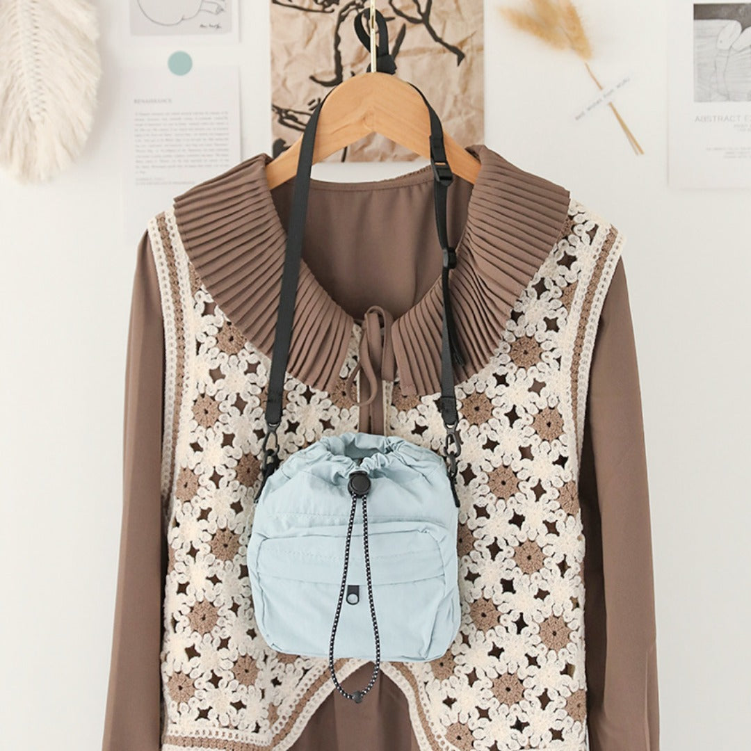 Light blue women's nylon drawstring bucket bag displayed on a fashionable outfit