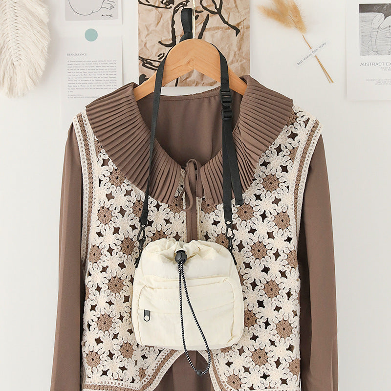 Elegant women's nylon drawstring bucket bag in cream attached to stylish outfit