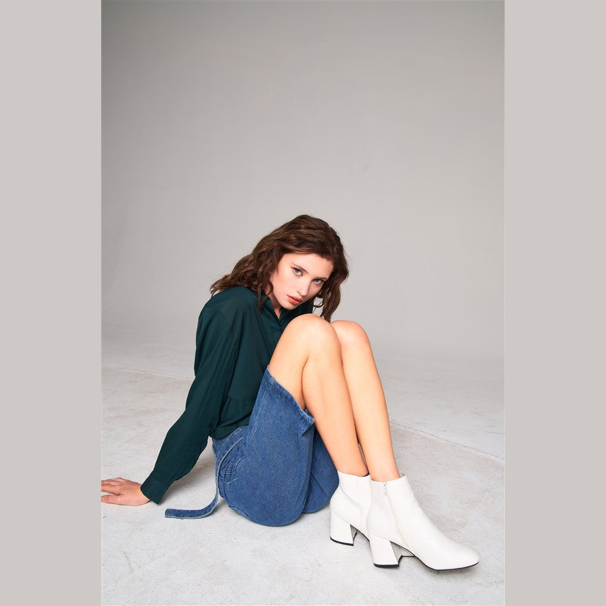 Woman wearing womens self-tie denim pants paired with white ankle boots and dark green top