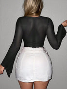 Back view of a woman wearing a black womens sexy navel exposed shirt paired with a white mini skirt