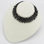 Womens statement necklace rhodium brass with intricate design, showcased on a display stand
