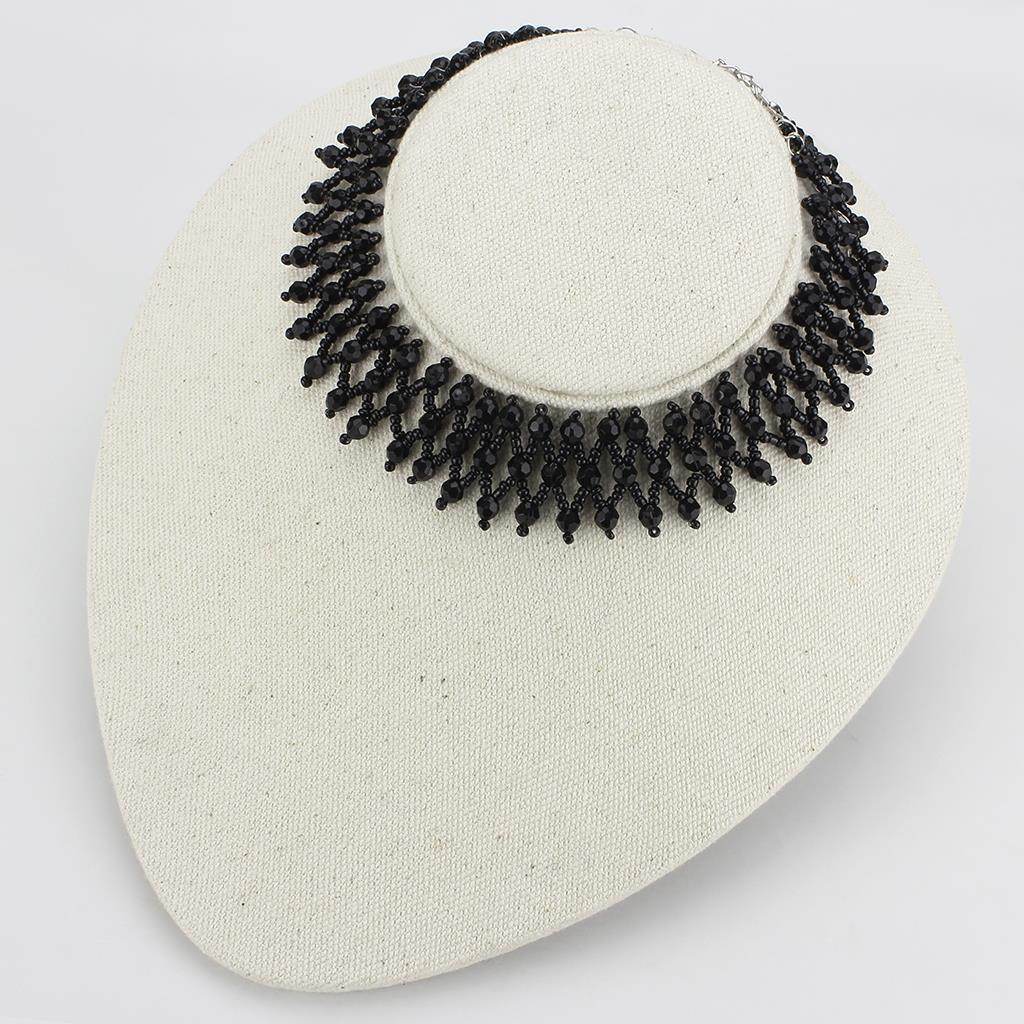 Womens statement necklace rhodium brass with intricate design, showcased on a display stand