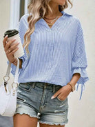 Casual women's striped blouse in blue and white with rolled sleeves, styled with denim shorts