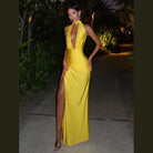 Model wearing a yellow halter deep v neck maxi dress with a thigh-high slit and elegant fit