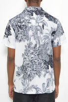 Back view of a black and white short sleeve shirt showcasing a tropical leaf print design