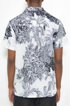 Back view of a black and white short sleeve shirt showcasing a tropical leaf print design