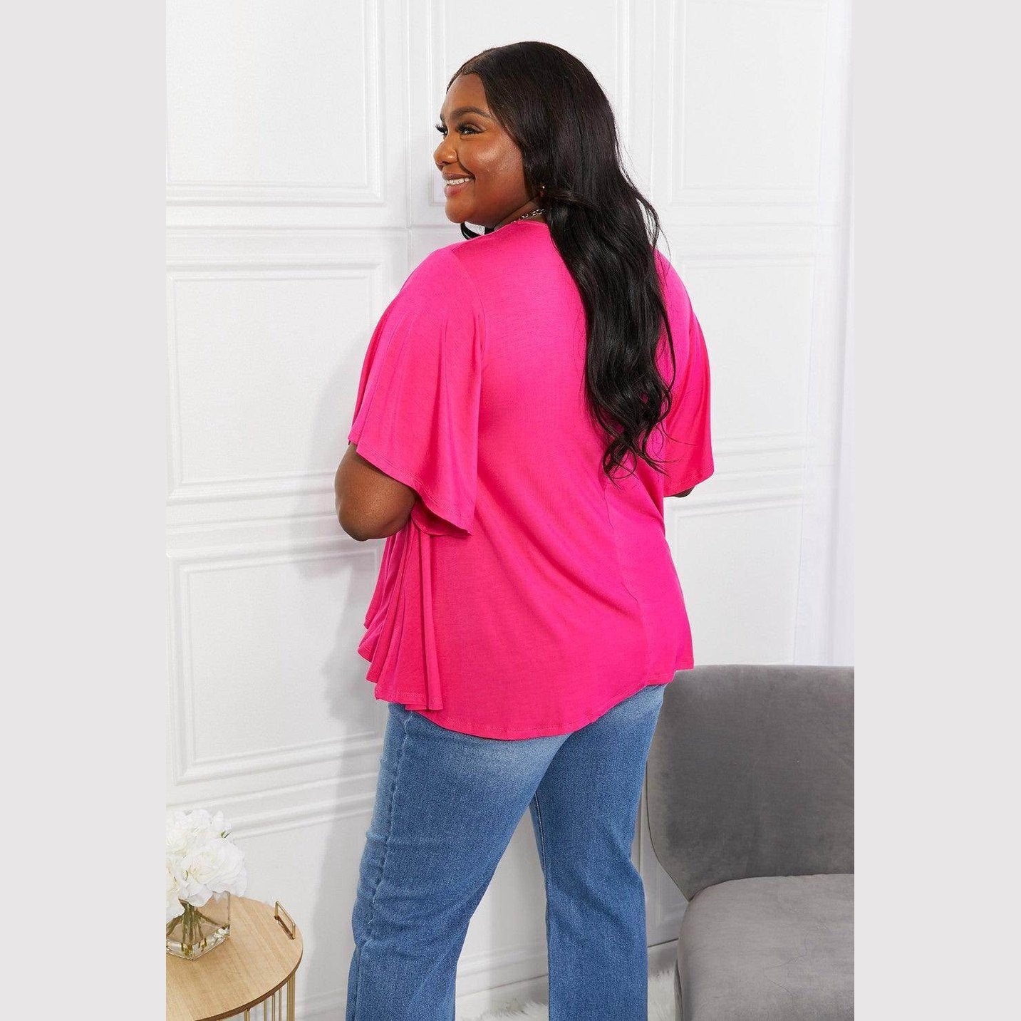 Back view of a woman wearing an elegant pink top paired with blue jeans for a stylish look