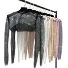 Variety of Women's Clubwear featuring glitter crop tops in multiple colors hanging on a rack