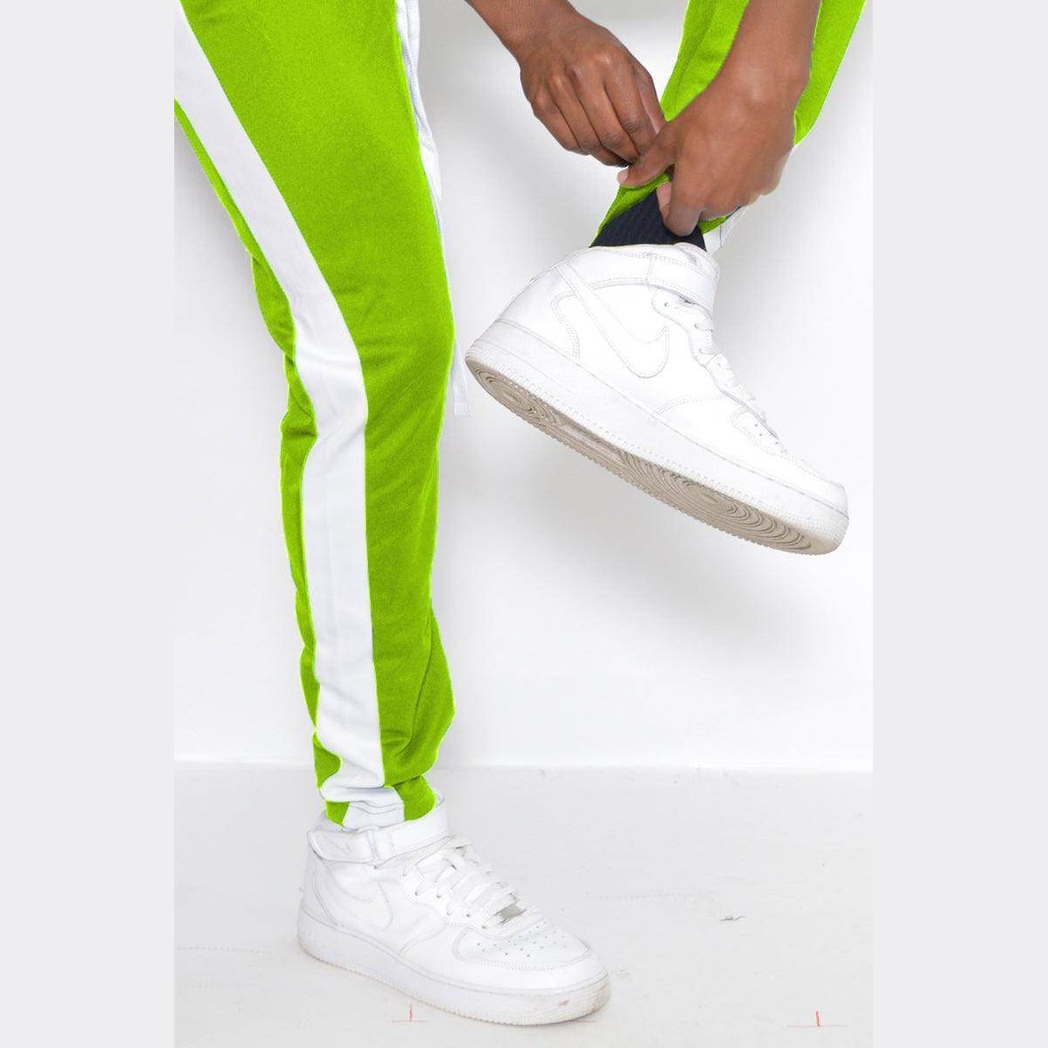 WEIV lime green track pants with white stripes, styled with white sneakers for a sporty look