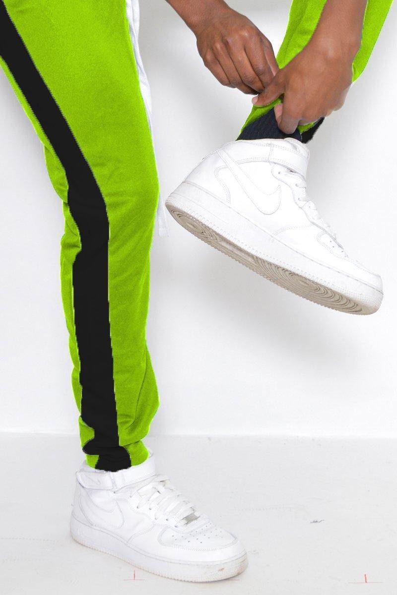 Lime green track pants men with black side stripes, styled with white sneakers for a sporty look