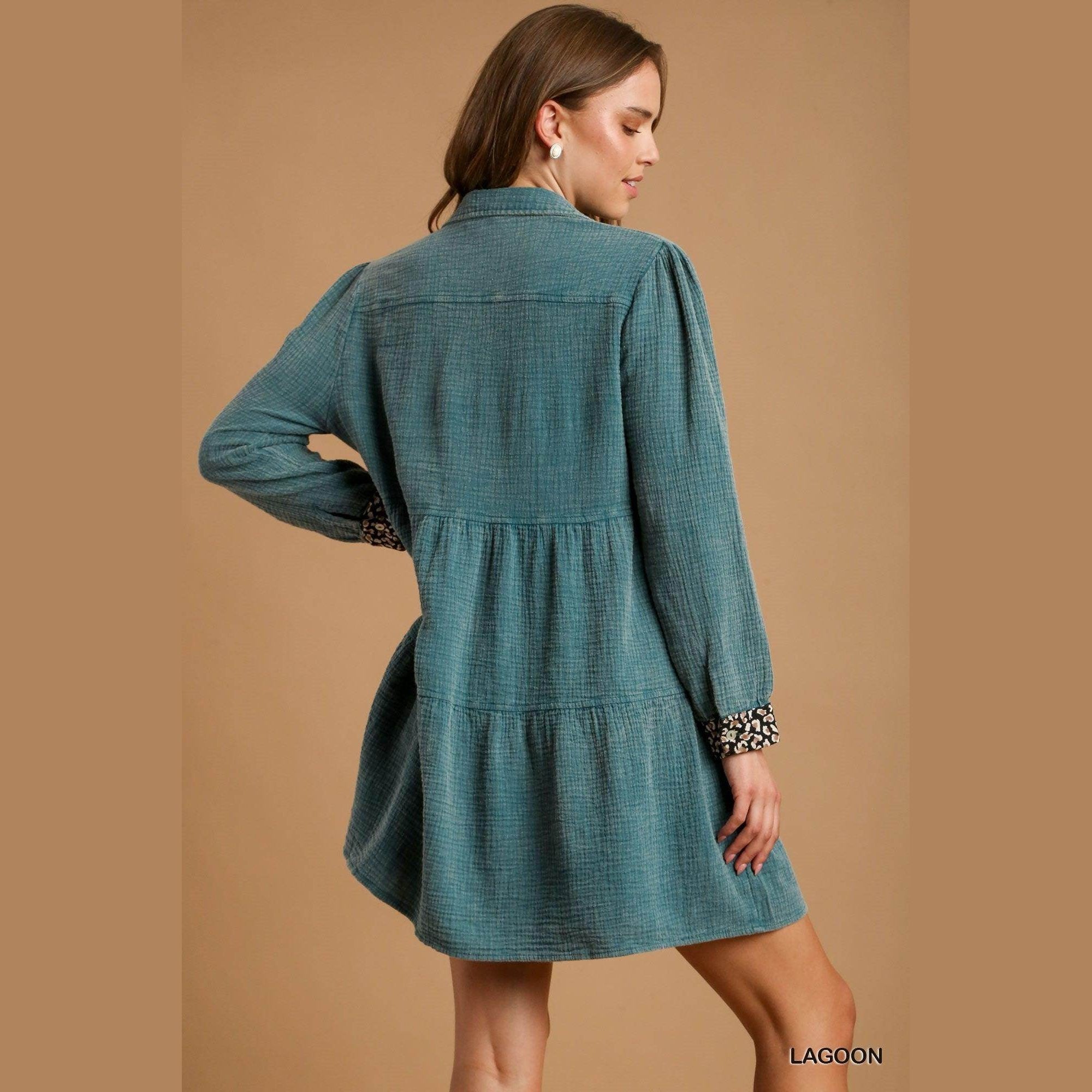 Back view of a mineral wash cotton dress in lagoon color, featuring tiered design and long sleeves