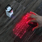 Hand using a mobile compatible keyboard projected on a wooden surface with a portable gadget beside it