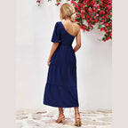 Back view of a navy stylish one-shoulder dress with puff sleeves and tiered design