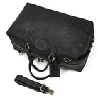 Vacation style leather bag in black with sturdy handles and detachable shoulder strap for travel convenience